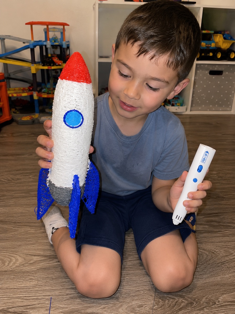 Une enfant recharge le stylo 3D Pen'Up 3D avec un filament Fil'Up